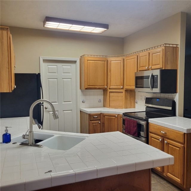 kitchen featuring backsplash, stainless steel appliances, sink, tile countertops, and light tile patterned flooring