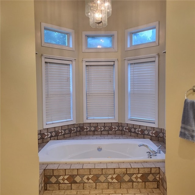 bathroom with a relaxing tiled tub and an inviting chandelier