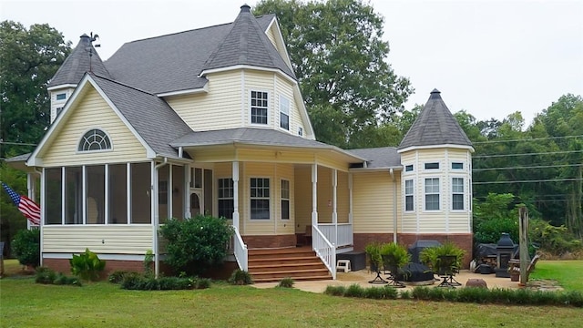 rear view of house featuring a sunroom, a yard, a patio, and an outdoor fire pit