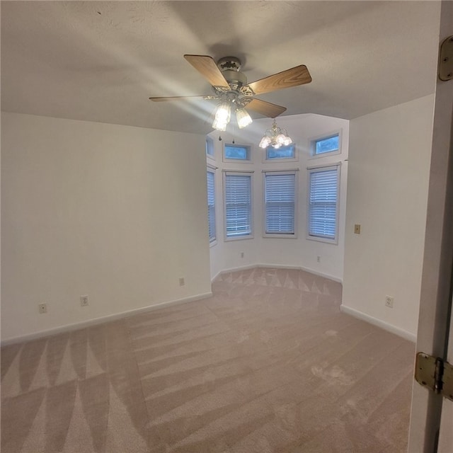 empty room featuring light carpet and ceiling fan with notable chandelier