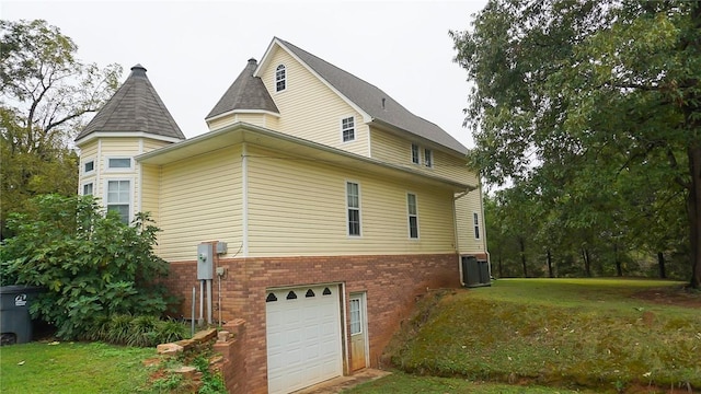 view of property exterior with a lawn, central air condition unit, and a garage