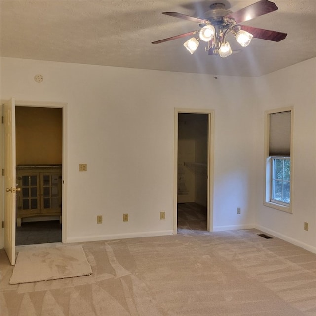 empty room with light carpet, ceiling fan, and a textured ceiling