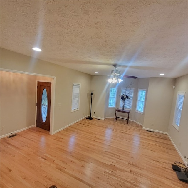 foyer with light wood-type flooring, a textured ceiling, and ceiling fan