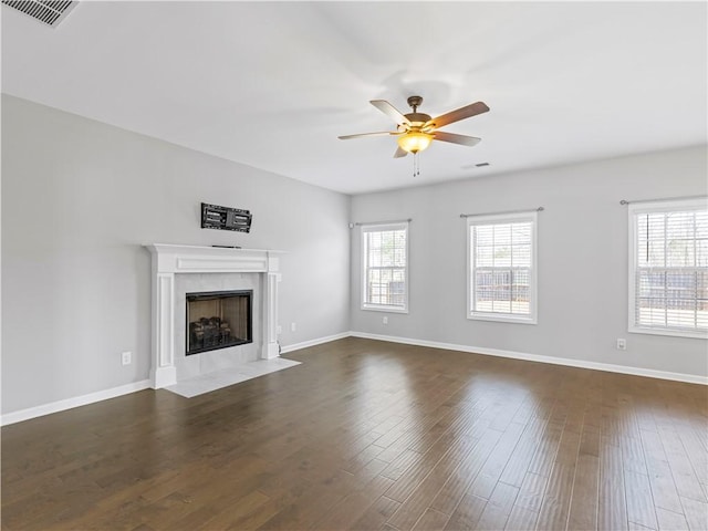 unfurnished living room featuring dark wood-style floors, visible vents, plenty of natural light, and a tile fireplace