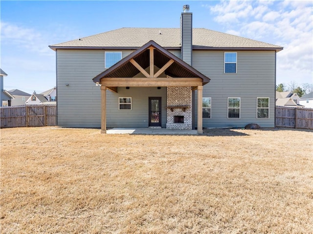 rear view of property featuring a yard, a fireplace, a fenced backyard, a chimney, and a patio area