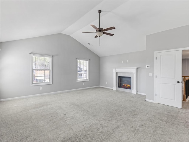 unfurnished living room featuring lofted ceiling, a ceiling fan, a glass covered fireplace, carpet floors, and baseboards