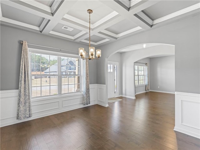 spare room featuring an inviting chandelier, wood finished floors, arched walkways, and visible vents