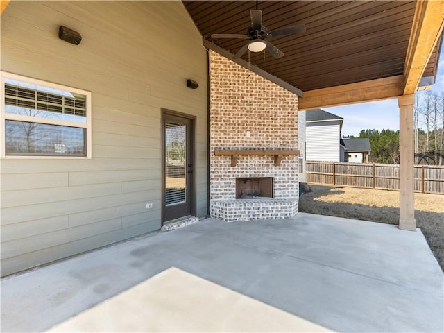 view of patio with fence, an outdoor brick fireplace, and ceiling fan