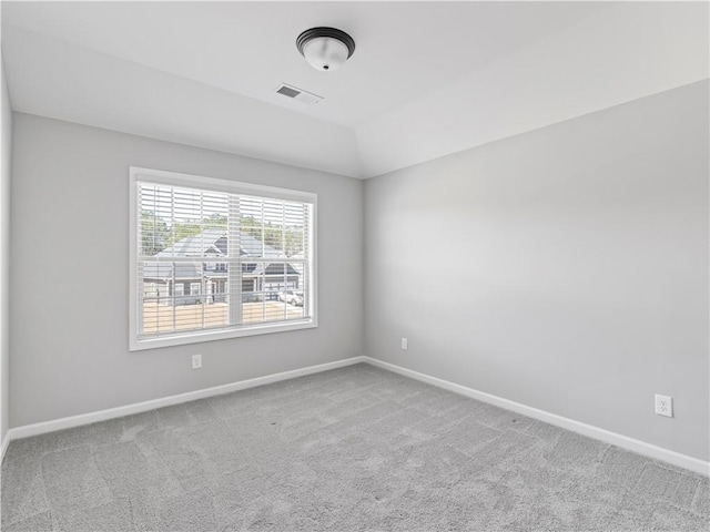 carpeted empty room featuring visible vents, baseboards, and vaulted ceiling