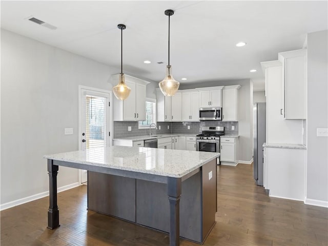 kitchen with visible vents, dark wood finished floors, white cabinets, appliances with stainless steel finishes, and tasteful backsplash