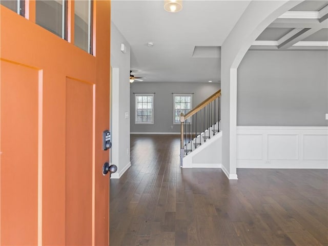 entrance foyer with stairs, a wainscoted wall, baseboards, and dark wood-style flooring