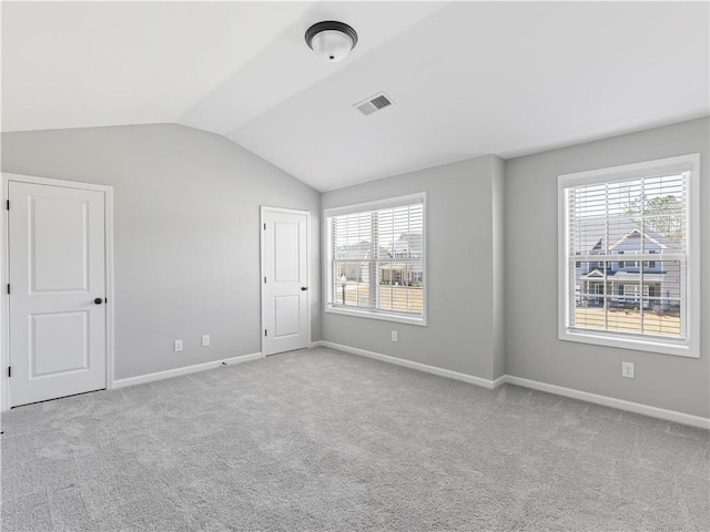 carpeted empty room with vaulted ceiling, baseboards, and visible vents