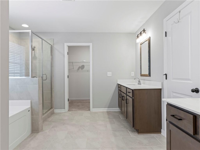 full bathroom featuring a spacious closet, a stall shower, vanity, and a bath