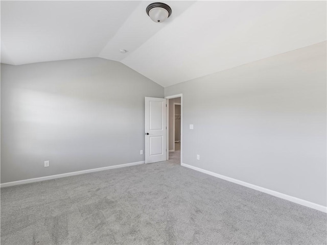 empty room with lofted ceiling, carpet flooring, and baseboards