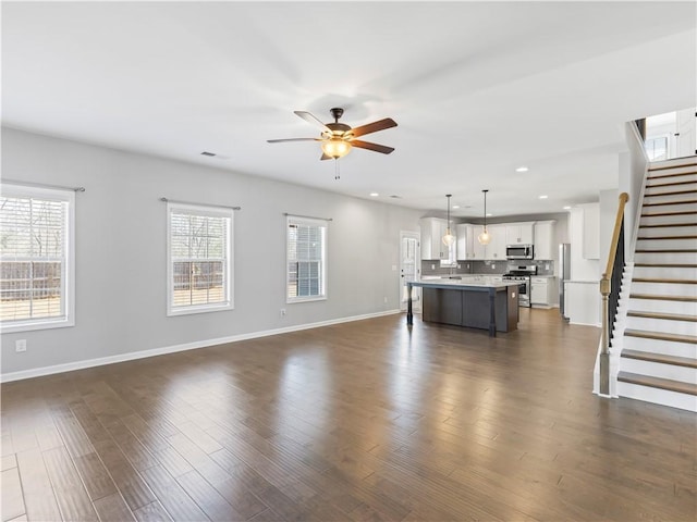 unfurnished living room with stairway, dark wood-style floors, baseboards, recessed lighting, and ceiling fan