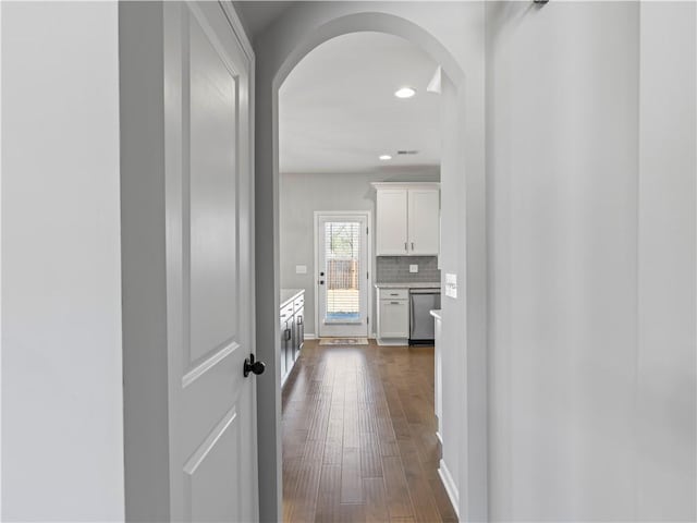 hallway featuring recessed lighting, baseboards, arched walkways, and dark wood-type flooring