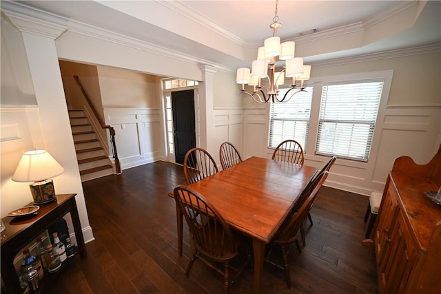 dining space featuring wainscoting, a decorative wall, dark wood-style flooring, and a notable chandelier