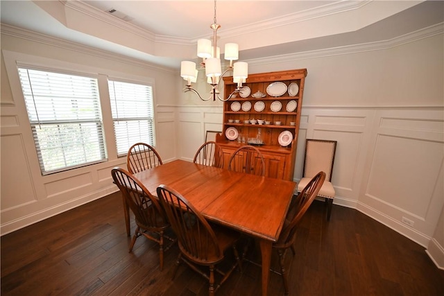 dining space featuring a notable chandelier, dark wood-style floors, a raised ceiling, and a decorative wall