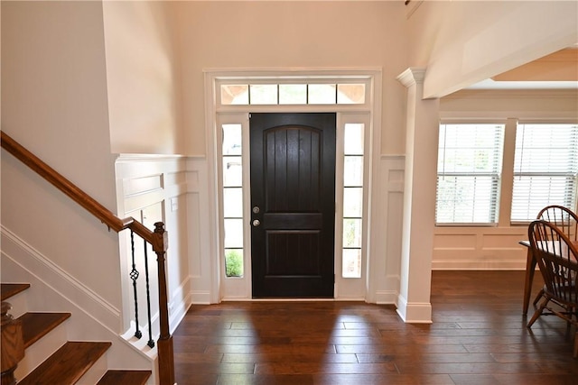 foyer featuring stairway, a decorative wall, and dark wood-type flooring