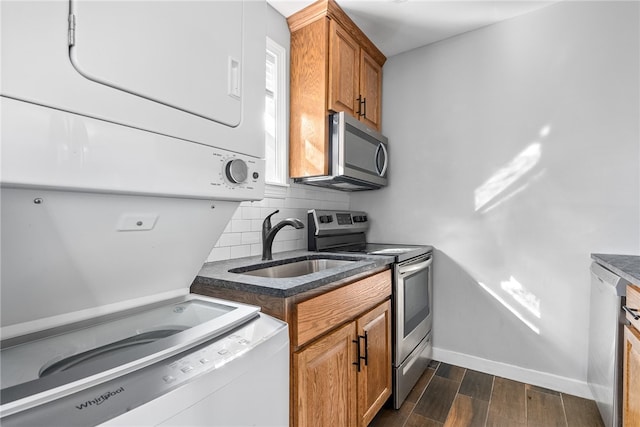 kitchen featuring backsplash, stainless steel appliances, stacked washer / dryer, and sink