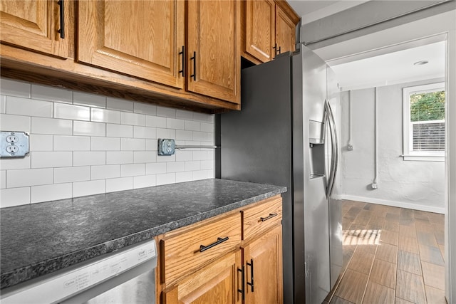 kitchen featuring dark stone counters, decorative backsplash, hardwood / wood-style floors, and stainless steel appliances