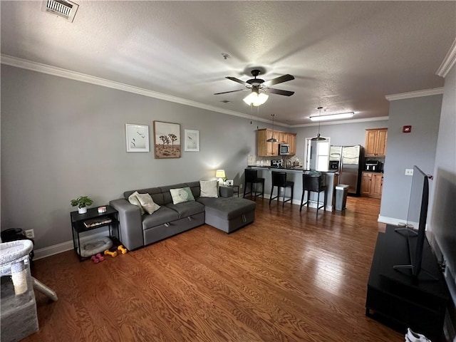 living area featuring a ceiling fan, visible vents, baseboards, dark wood-type flooring, and crown molding