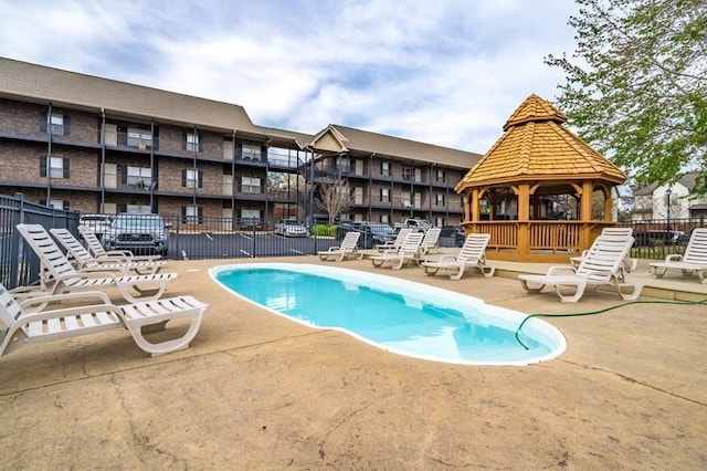 community pool with a gazebo, a patio area, and fence