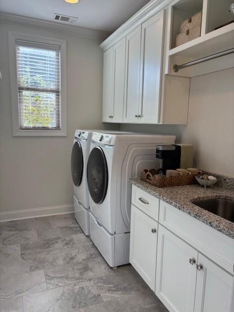 laundry area featuring washing machine and dryer, ornamental molding, and cabinets