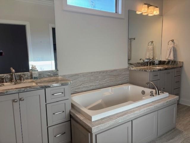 bathroom with hardwood / wood-style floors, crown molding, vanity, and a bathing tub