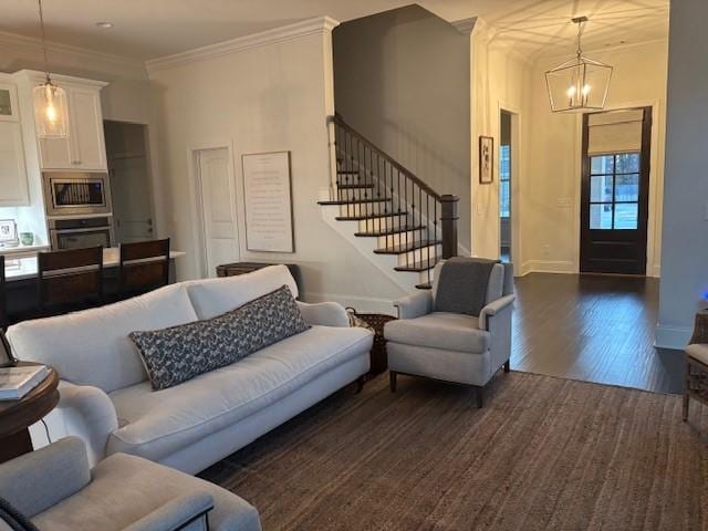 living room featuring dark wood-type flooring, ornamental molding, and a chandelier