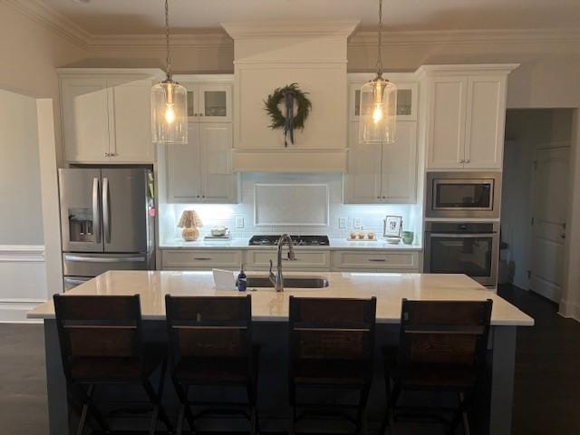 kitchen featuring a center island with sink, white cabinetry, pendant lighting, and appliances with stainless steel finishes