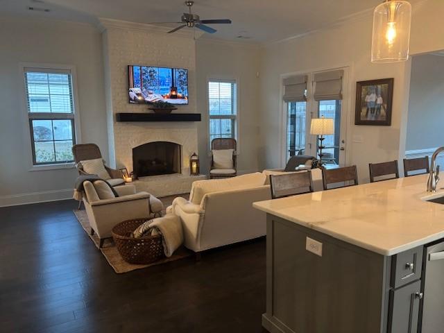 living room with a fireplace, ceiling fan, a wealth of natural light, and dark wood-type flooring