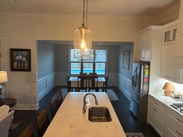 kitchen with sink, white cabinetry, ornamental molding, a breakfast bar area, and hanging light fixtures