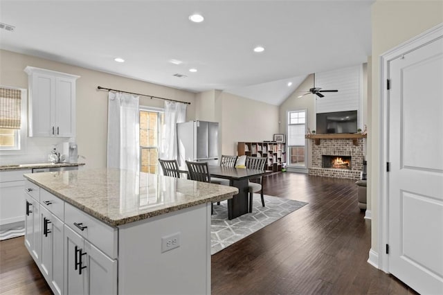 kitchen with white cabinetry, a wealth of natural light, light stone countertops, and a center island