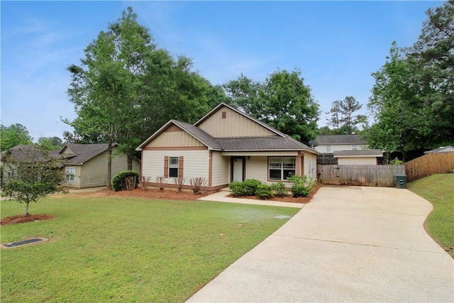 view of front of property with concrete driveway, fence, and a front lawn