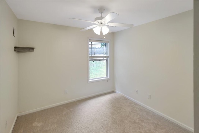 spare room with baseboards, light carpet, and ceiling fan