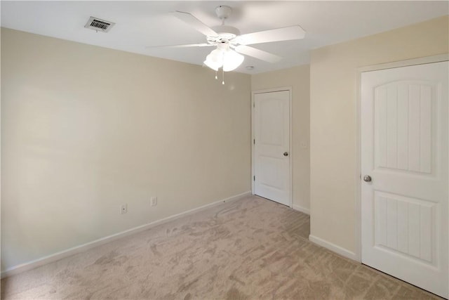 unfurnished room featuring baseboards, ceiling fan, light colored carpet, and visible vents