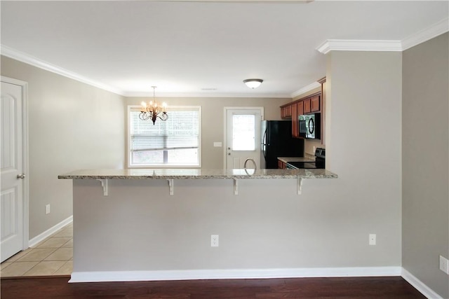 kitchen featuring freestanding refrigerator, electric range, a peninsula, a breakfast bar, and a chandelier