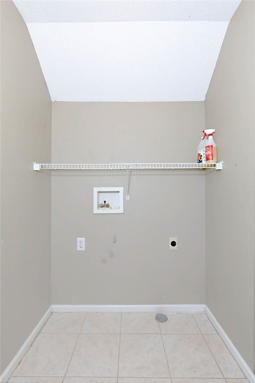 laundry room with hookup for an electric dryer, hookup for a washing machine, baseboards, and light tile patterned flooring