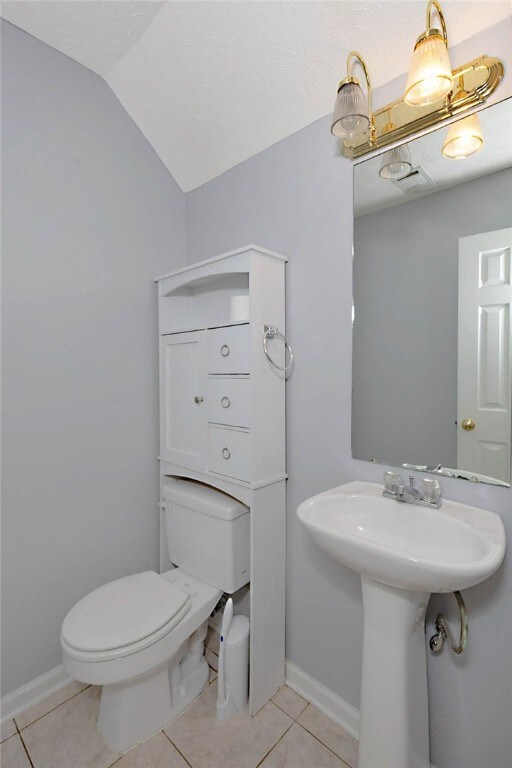 bathroom featuring tile patterned flooring, toilet, vaulted ceiling, and baseboards