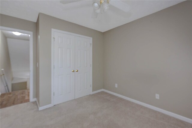unfurnished bedroom with light colored carpet, a closet, baseboards, and a ceiling fan