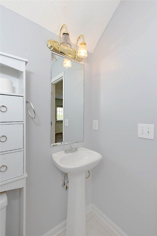 bathroom featuring baseboards, tile patterned flooring, and vaulted ceiling