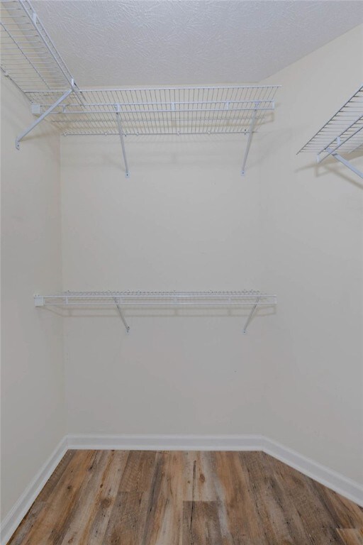 walk in closet with wood finished floors