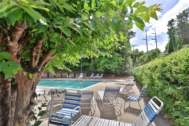 community pool with a patio area and fence