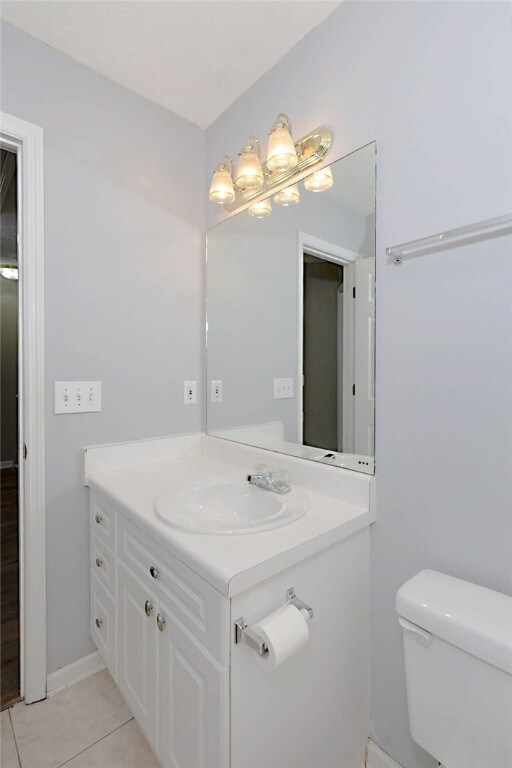 half bath featuring toilet, vanity, and tile patterned flooring