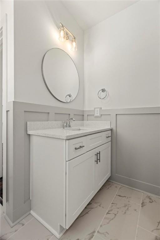 bathroom with marble finish floor, wainscoting, and vanity