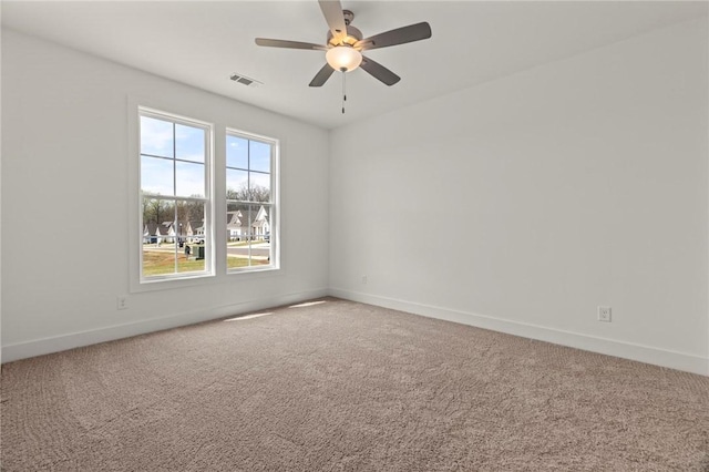 carpeted spare room featuring visible vents, ceiling fan, and baseboards