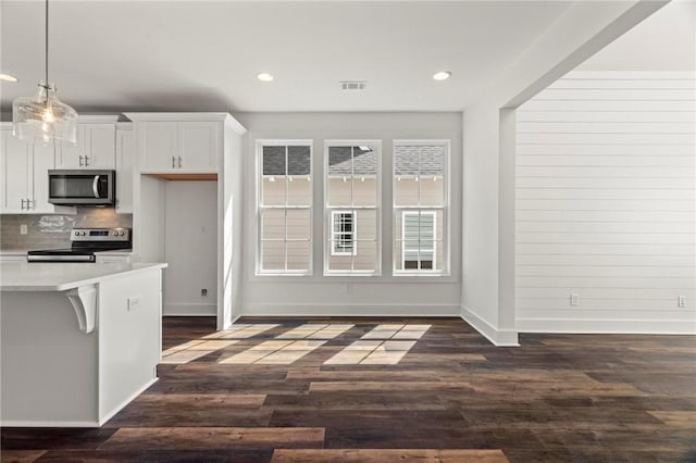 kitchen featuring dark wood-style flooring, light countertops, appliances with stainless steel finishes, white cabinetry, and tasteful backsplash