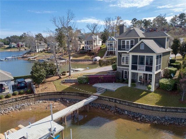 back of house featuring a patio, a water view, a yard, stone siding, and a residential view