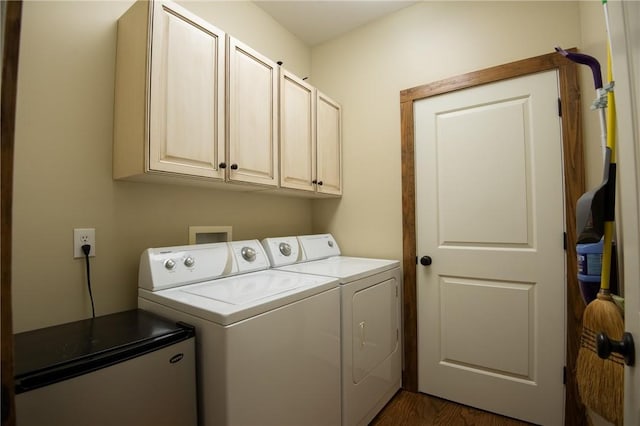 washroom with dark wood-type flooring, washing machine and clothes dryer, and cabinet space